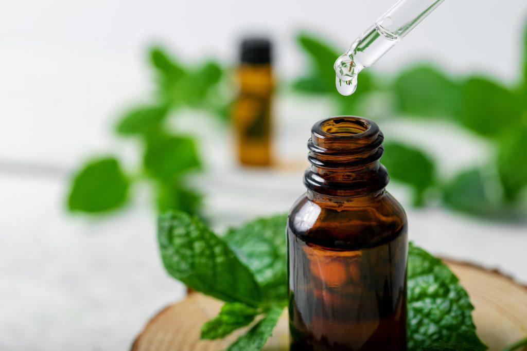 mint oil being dropped into sample vial surrounded by mint leaves